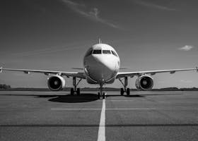 Front view of an airplane parked on a runway in a striking black and white photo.