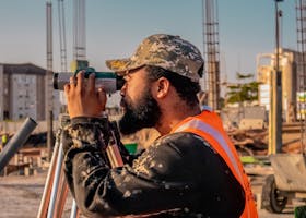 A construction worker uses a theodolite on a building site, capturing precise measurements.