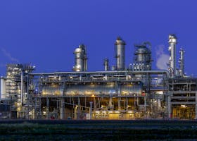 A striking view of an industrial facility in Zuid-Holland, illuminated at dusk against a clear blue sky.